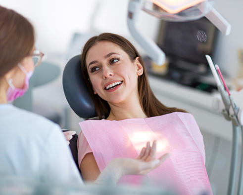 Female patient sitting in dental chair and talking to dentist