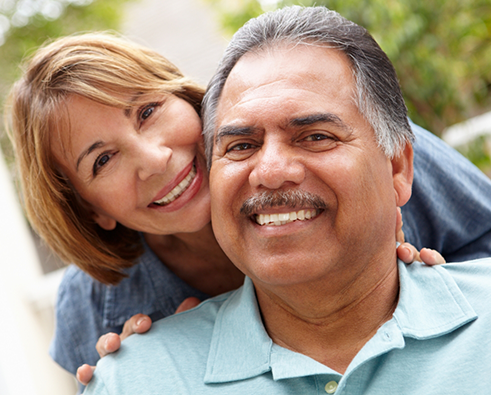 Man smiling with woman putting hand on shoulders from behind