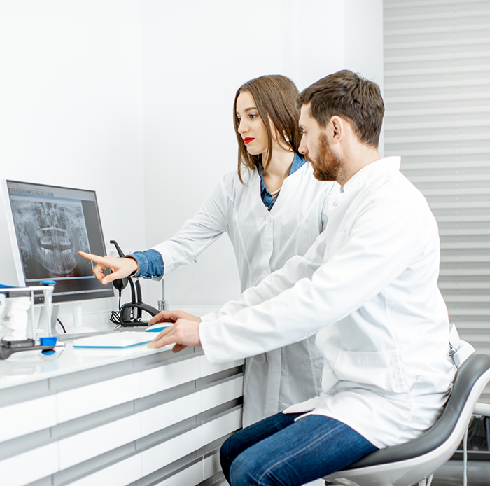 Male and female dentist looking at monitor