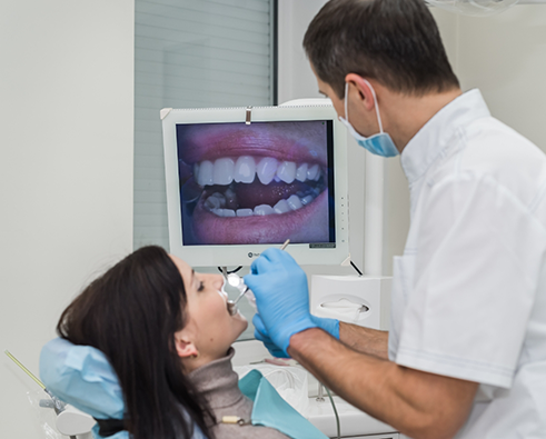 Dentist using intraoral camera to examine patients teeth