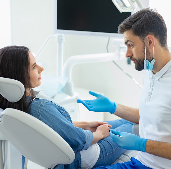 Male dentist speaking to female patient