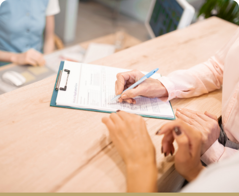 Filling out insurance form on clipboard with pen