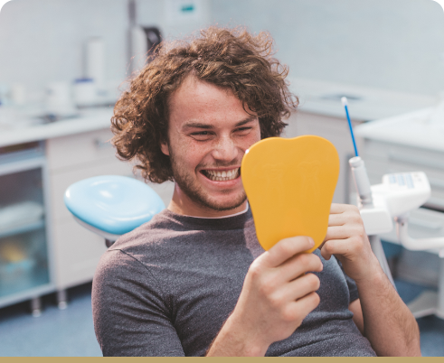 Male dental patient checking smile in mirror