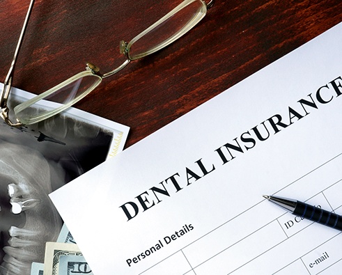 Dental insurance document with X-ray and glasses