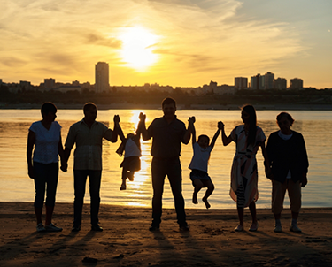 Several people holding hands in a row watching a sunset