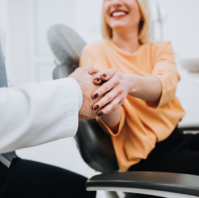 Woman in dental chair shaking hand of dentist in Houston