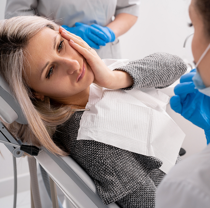 Woman with tooth pain looking up at dentist