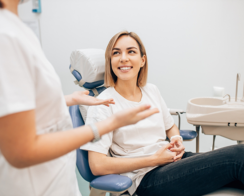 Smiling female dental patient looking up at dentist