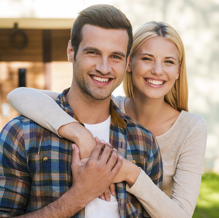 Young couple smiling with woman hugging man