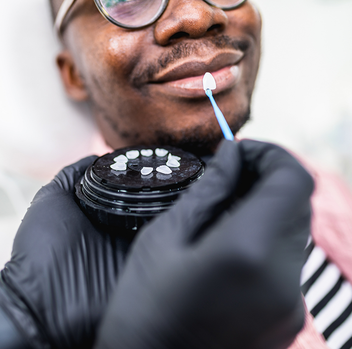 Dentist holding veneers in Houston in front of a smiling man