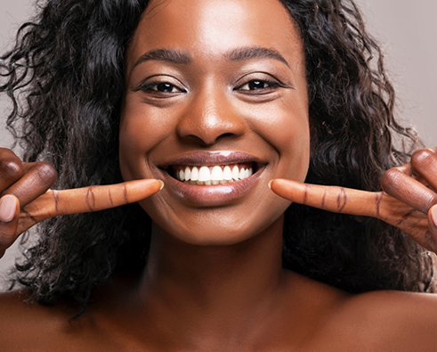 Close up of woman pointing to her smile